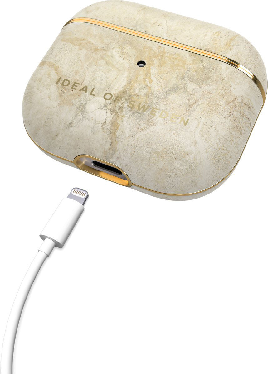 Achterkant van iDeal of Sweden AirPods-hoesje met beige marmerpatroon en losse oplaadkabel
